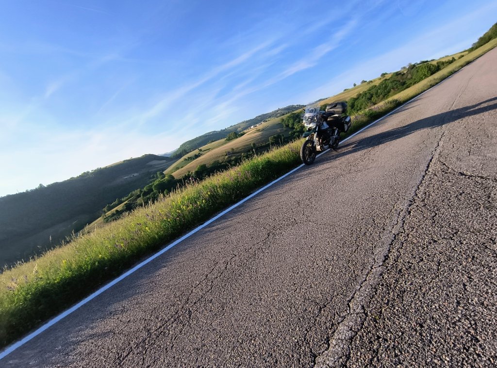 IMMAGINE DI MOTOGUZZI SU STRADA DESERTA IN PIANURA PADANA TRA CAMPI