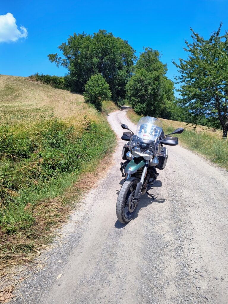moto guzzi v85tt mentr sosta su strada bianca appenninica un sbato assolato di giugno.